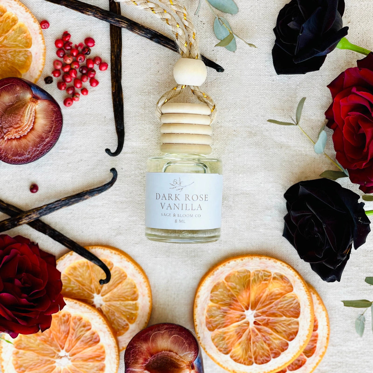 Dark Rose Vanilla car diffuser flat lay with black roses, pink peppercorn, grapefruit, plum and vanilla