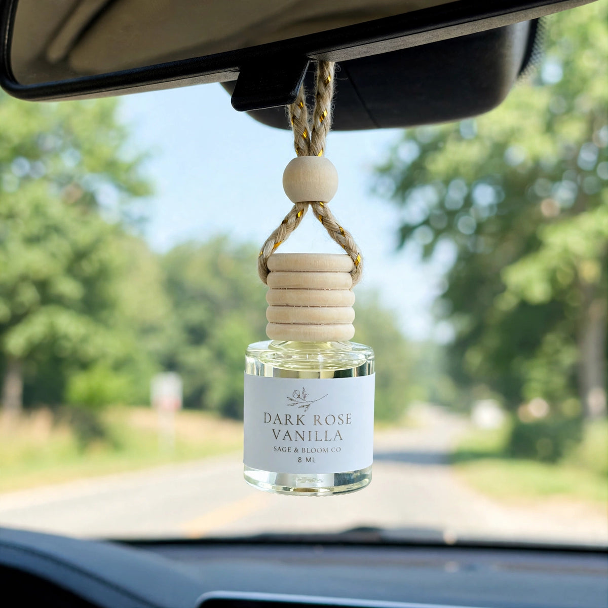 Dark Rose Vanilla car diffuser hanging from a rearview mirror on a summer drive