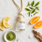 Matcha Bergamot car diffuser flat lay with matcha, lemon, orange, tea leaves, sea salt and sandalwood