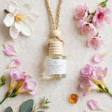 Magnolia Peony car diffuser flat lay with magnolia, peony petals, freesia, cherry blossom and amber