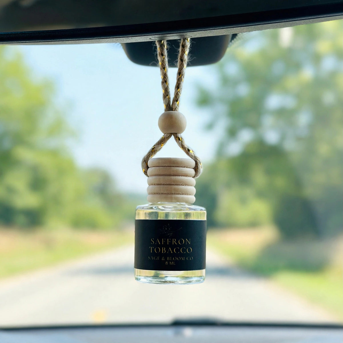Saffron Tobacco car diffuser hanging behind the rearview mirror on a summer drive