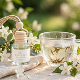 White Tea Jasmine car diffuser beside a glass cup of white tea with jasmine flowers