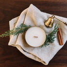 Gilded Rose and Spruce travel tin candle on natural linen with brass snuffer
