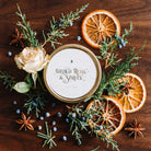 Gilded Rose and Spruce travel tin candle with a gilded rose on dark walnut