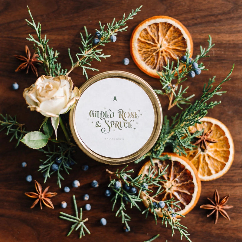 Gilded Rose and Spruce travel tin candle with a gilded rose on dark walnut