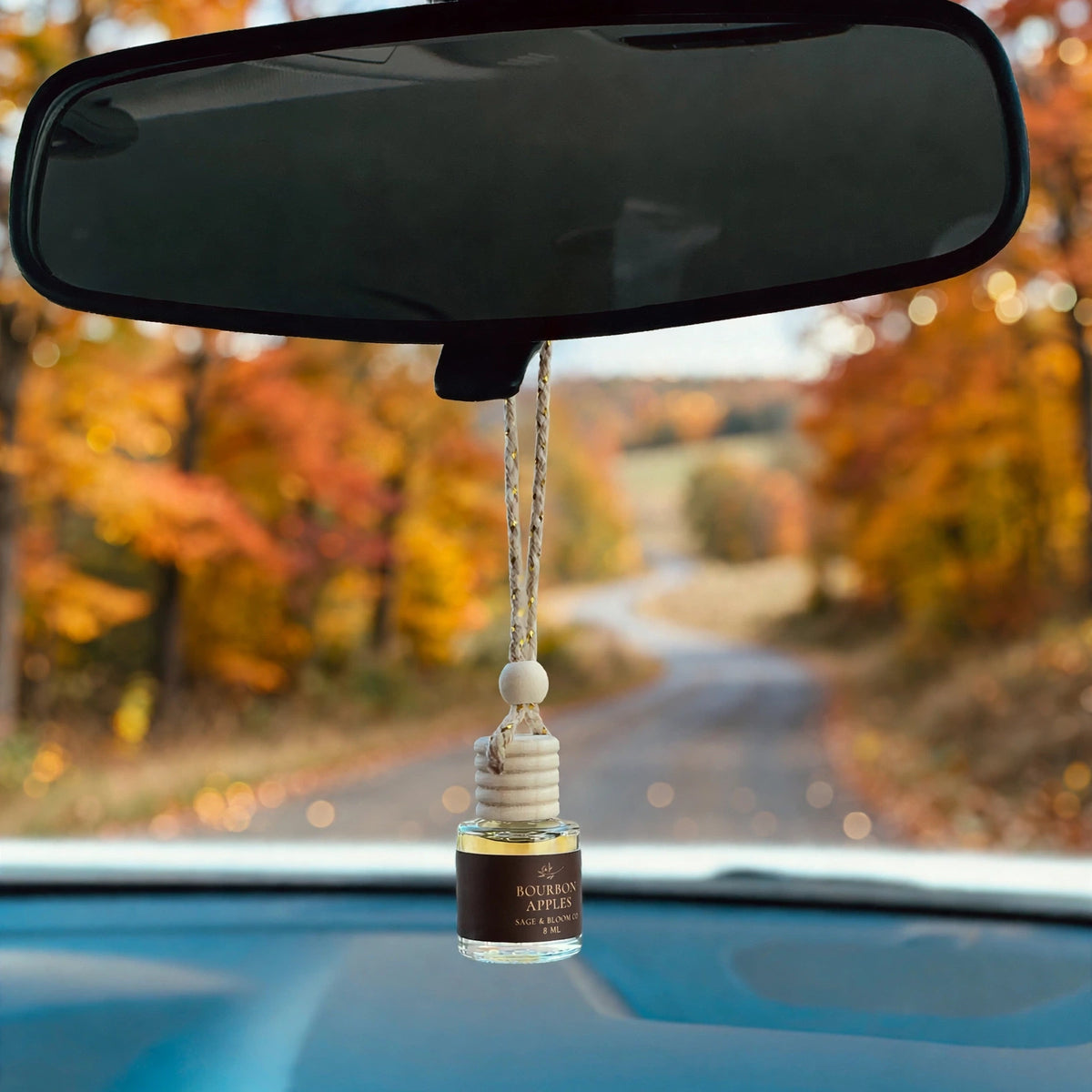 Bourbon Apples car diffuser hanging in car with fall landscape