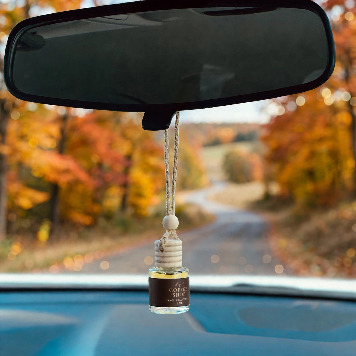 Coffee Shop car diffuser hanging in car with fall landscape