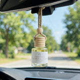 Camellia Patchouli Flower car diffuser hanging from a rearview mirror on a summer drive