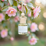 Camellia Patchouli Flower car diffuser hanging from a blooming camellia branch
