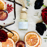 Dark Rose Vanilla car diffuser flat lay with black roses, pink peppercorn, grapefruit, plum and vanilla
