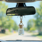 Matcha Bergamot car diffuser hanging behind the rearview mirror on a summer drive