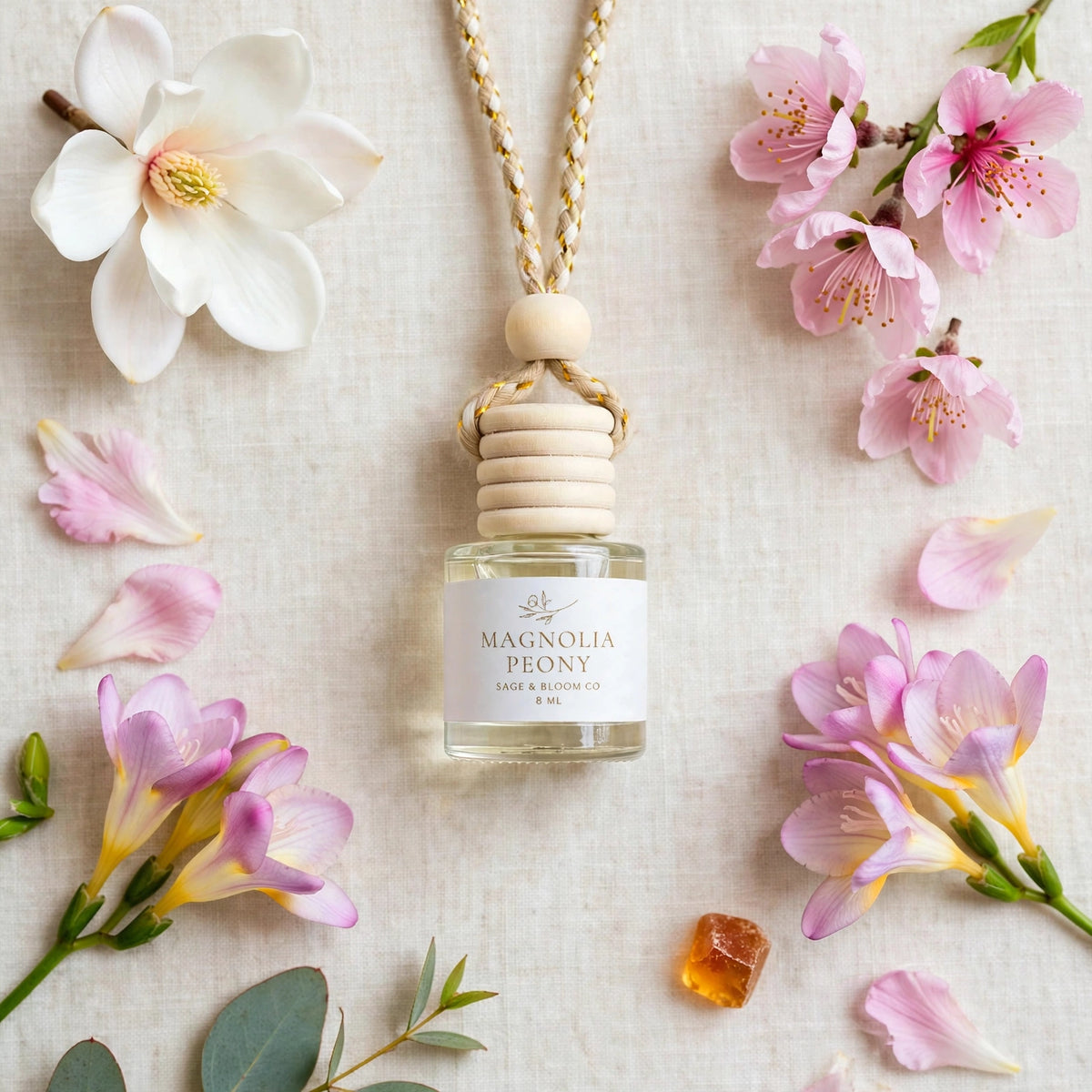 Magnolia Peony car diffuser flat lay with magnolia, peony petals, freesia, cherry blossom and amber