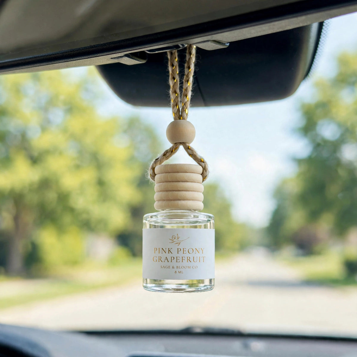 Pink Peony Grapefruit car diffuser hanging behind the rearview mirror on a summer drive