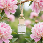 Pink Peony Grapefruit car diffuser hanging from a peony branch