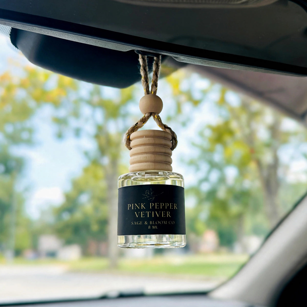 Pink Pepper Vetiver car diffuser hanging behind the rearview mirror on a summer drive