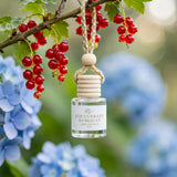 Red Currant Kumquat car diffuser hanging from a red currant branch