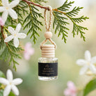 Rouge Saffron car diffuser hanging from a cedar branch with jasmine