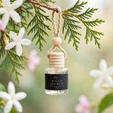 Rouge Saffron car diffuser hanging from a cedar branch with jasmine
