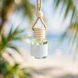 Salted Coconut car diffuser hanging among palm fronds at the beach