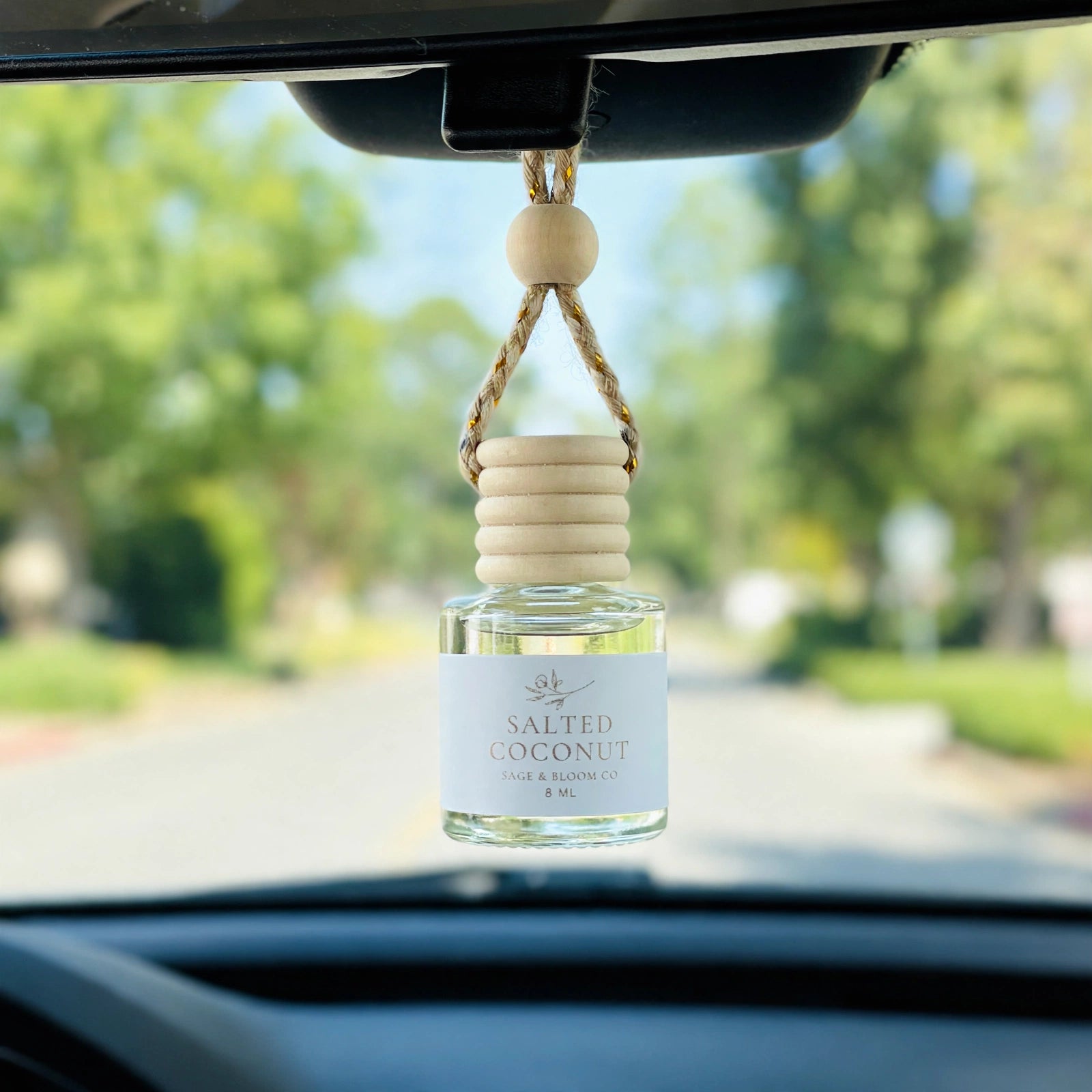 Salted Coconut car diffuser hanging from a rearview mirror on a summer drive