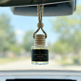 Sandalwood Smoke car diffuser hanging behind the rearview mirror on a summer drive