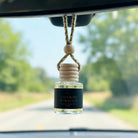 Saffron Tobacco car diffuser hanging behind the rearview mirror on a summer drive