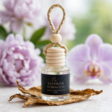 Saffron Tobacco car diffuser against light purple peonies with tobacco leaves