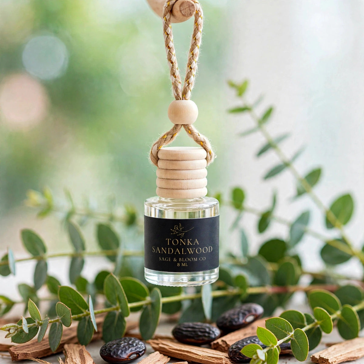 Tonka Sandalwood car diffuser hanging among eucalyptus branches with tonka beans