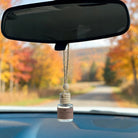 Quince Ambrosia Oats car diffuser hanging in car with fall landscape