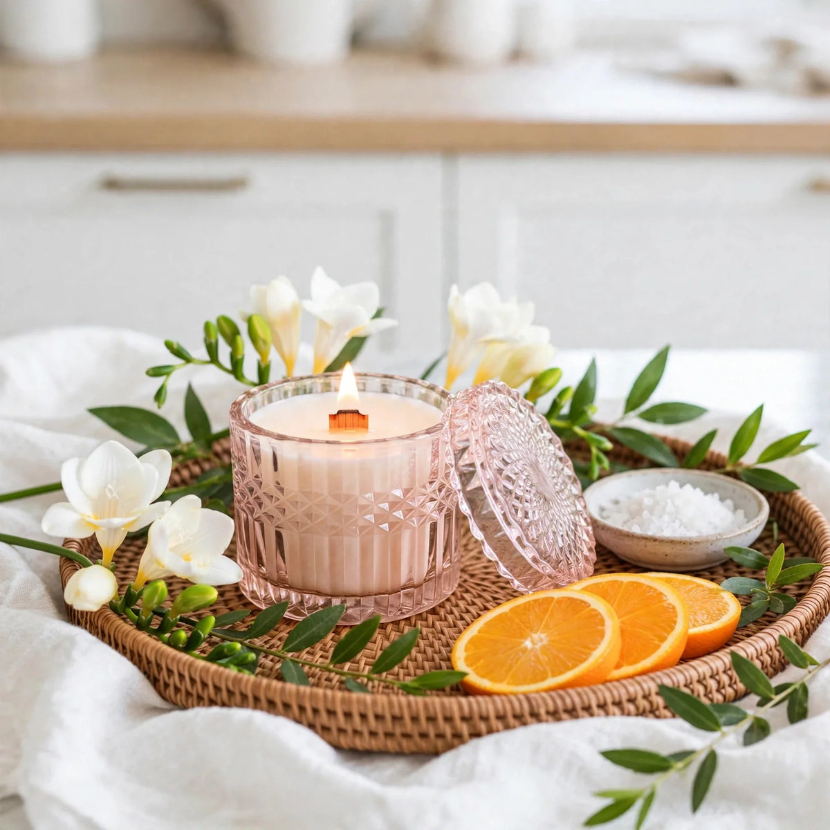 Sea Salt Orchid Vintage Glass Candle in blush glass vessel with lid beside it, styled with freesia and sea salt