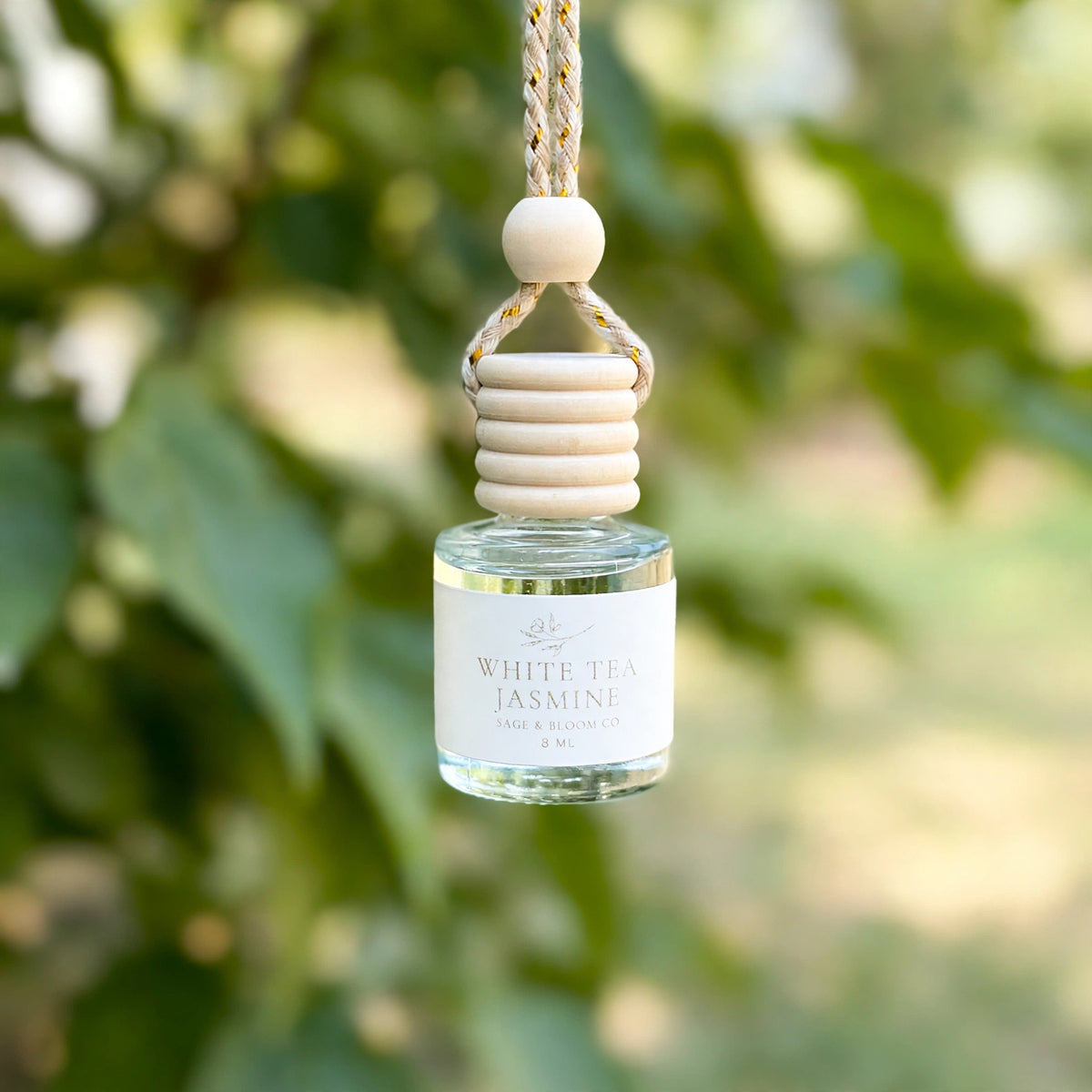 White Tea Jasmine car diffuser hanging against soft summer greenery