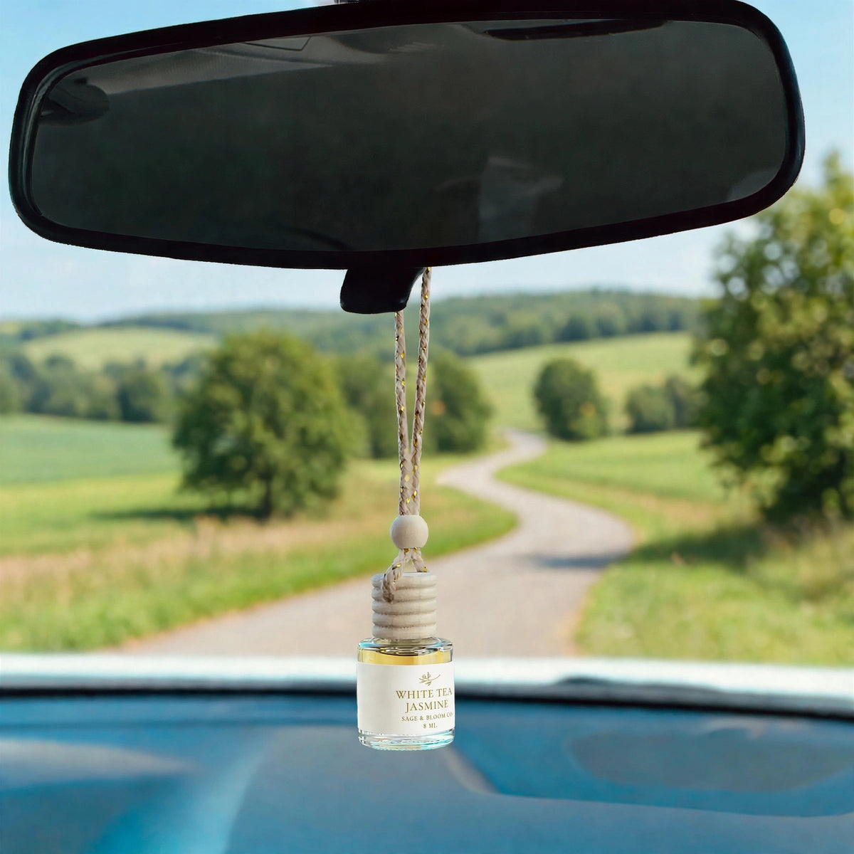 White Tea Jasmine car diffuser hanging from a rearview mirror on a summer drive