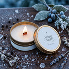 Lit Nordic Nights travel tin candle with wooden wick on frosted walnut
